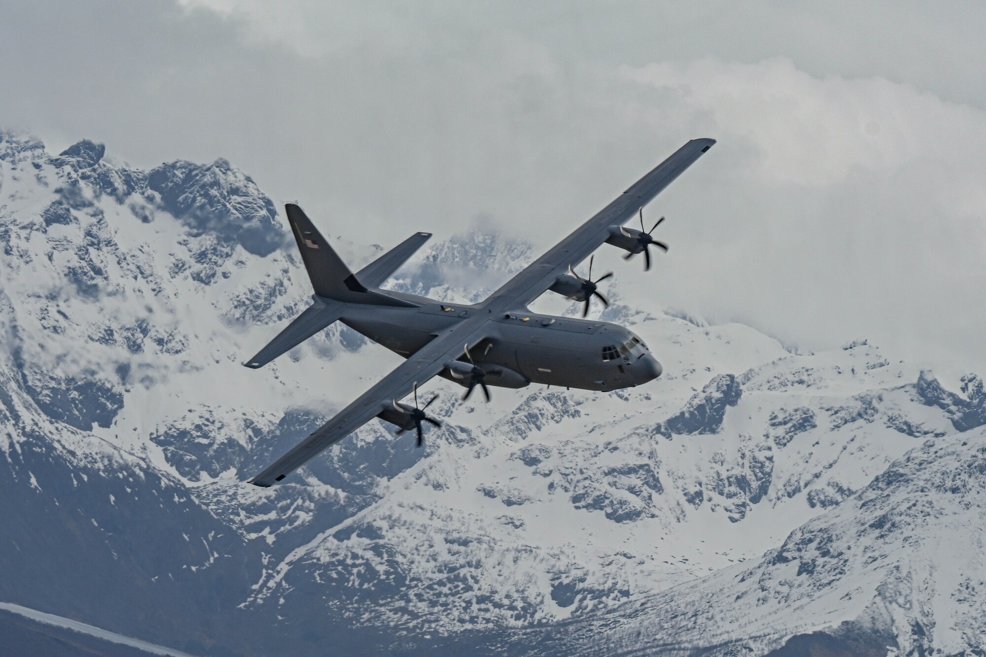 An C-130 aircraft flies through the sky.