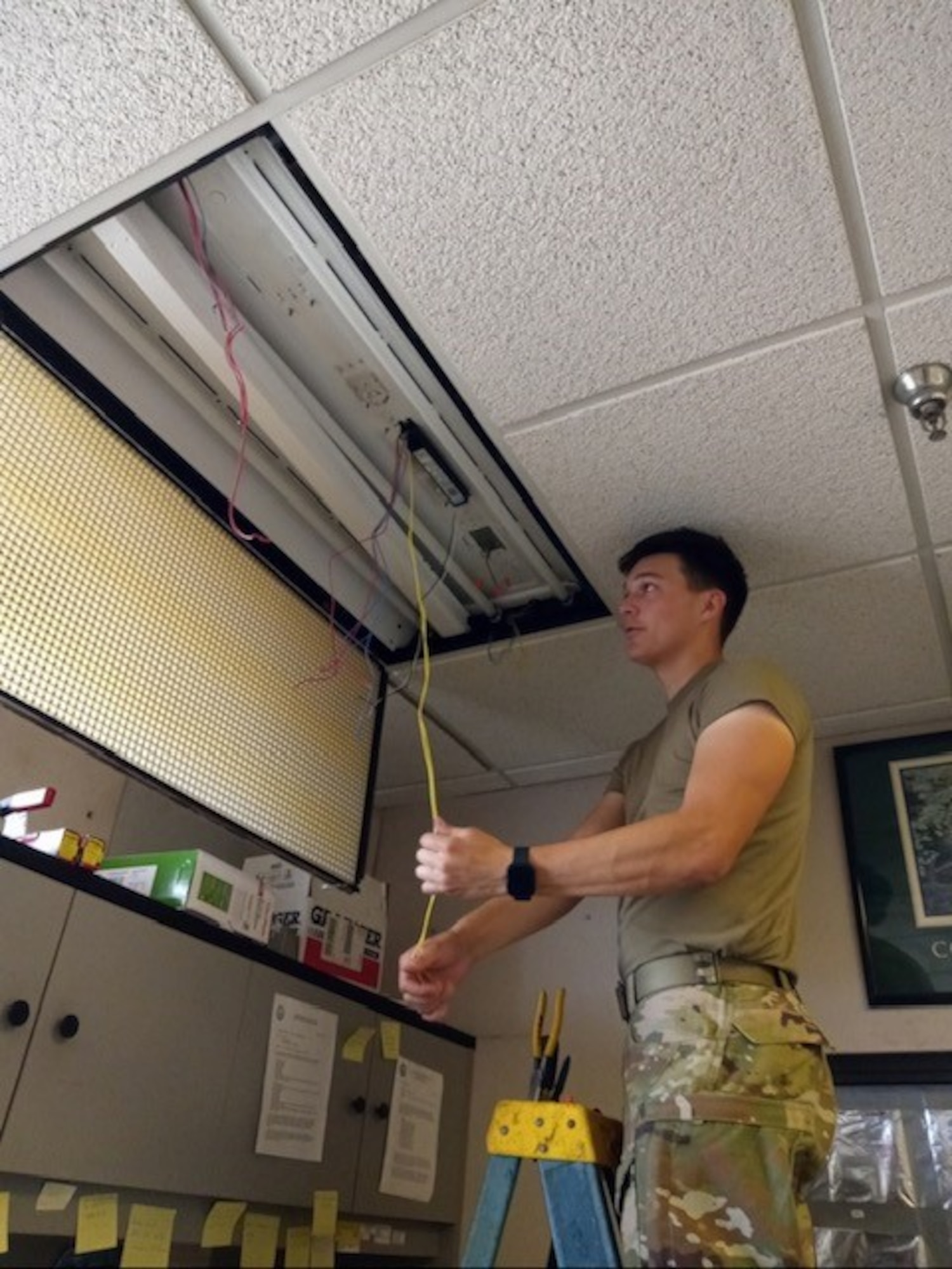 U.S Air Force Airman 1st Class Noah Melero, 97th Civil Engineer Squadron electrical systems apprentice, converts ceiling lighting to LED bulbs at Altus Air Force Base, Oklahoma. Melero worked outside his career field assisting the fire alarm system technicians to conduct preventative maintenance. (Courtesy photo by Donald Haden)