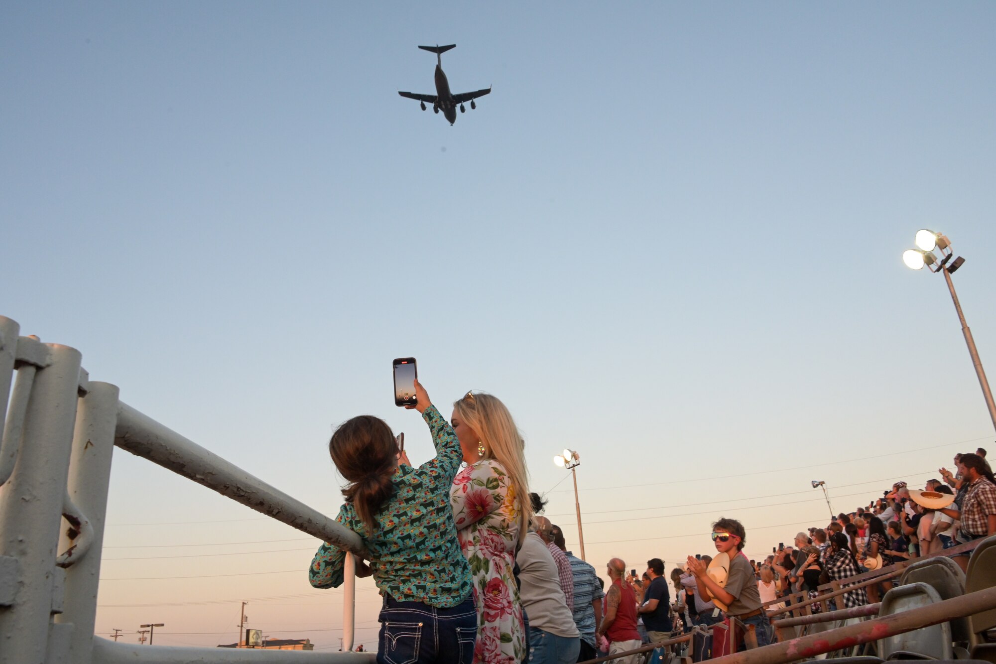 A C-17 Globemaster III aircraft flies over the Great Plains Stampede Rodeo in Altus Oklahoma, Aug. 22, 2024. The military appreciation night at the Great Plains Stampede Rodeo arena included events like the barrel racing, bull and bronco riding and steer wrestling. (U.S. Air Force photo by Airman 1st Class Lauren Torres)