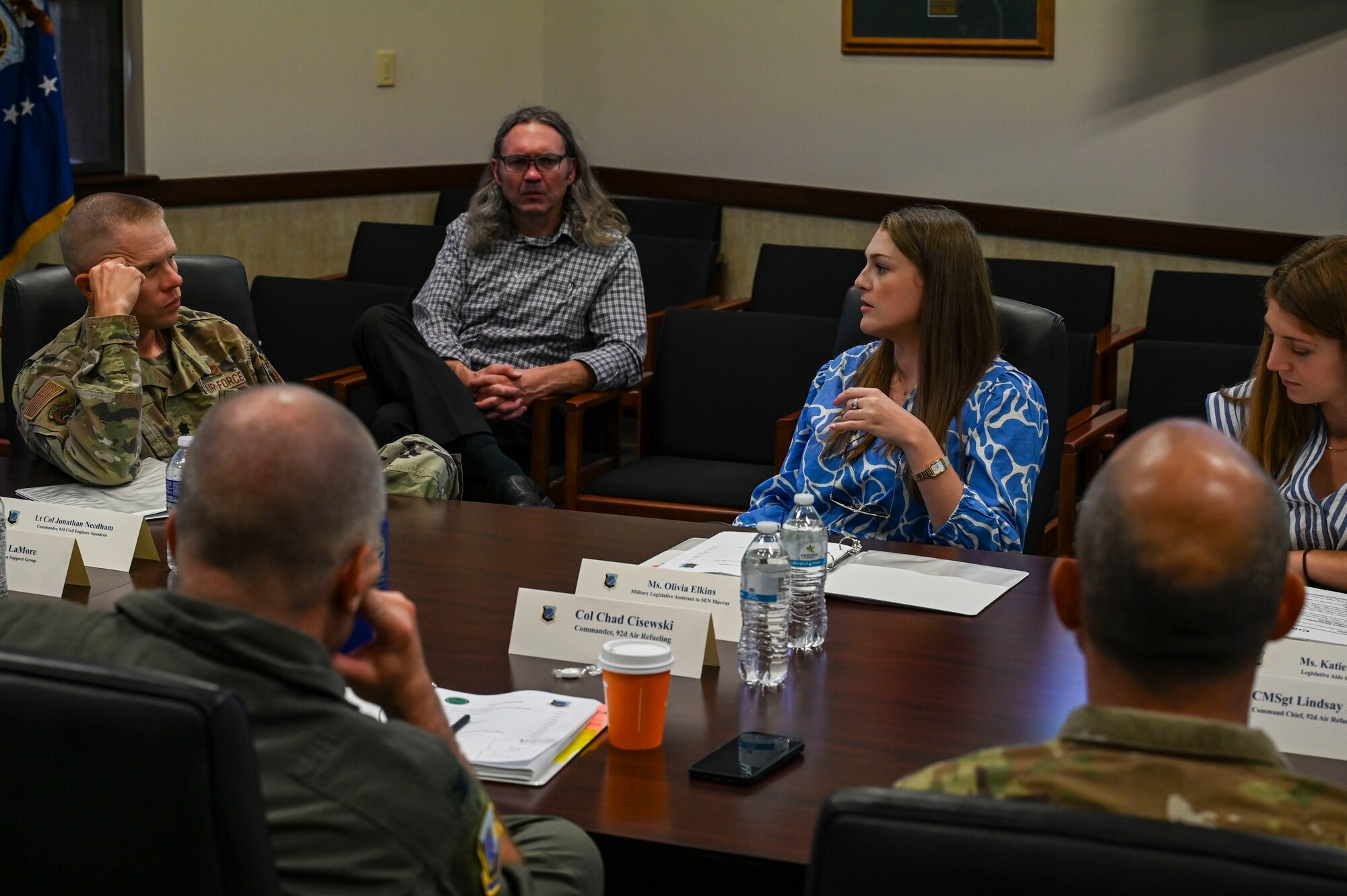 Airmen and civilians speak to each other in a conference room.