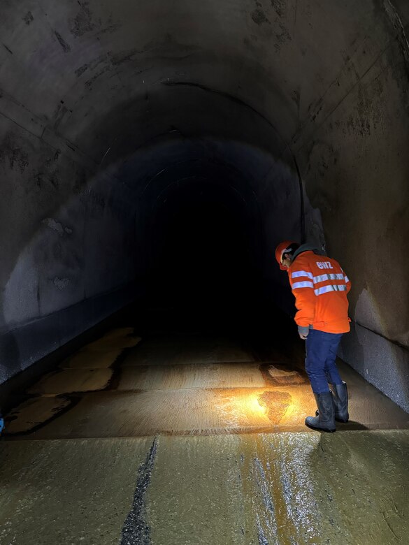 A Swiss engineer investigates a worn area in the Solis sediment bypass tunnel. At about 18 feet by 18 feet, this tunnel is nearly the same size as the proposed dimensions for the upcoming project at Lowell Creek in Alaska. (Photo by Carly Lynch, USACE – Alaska District)