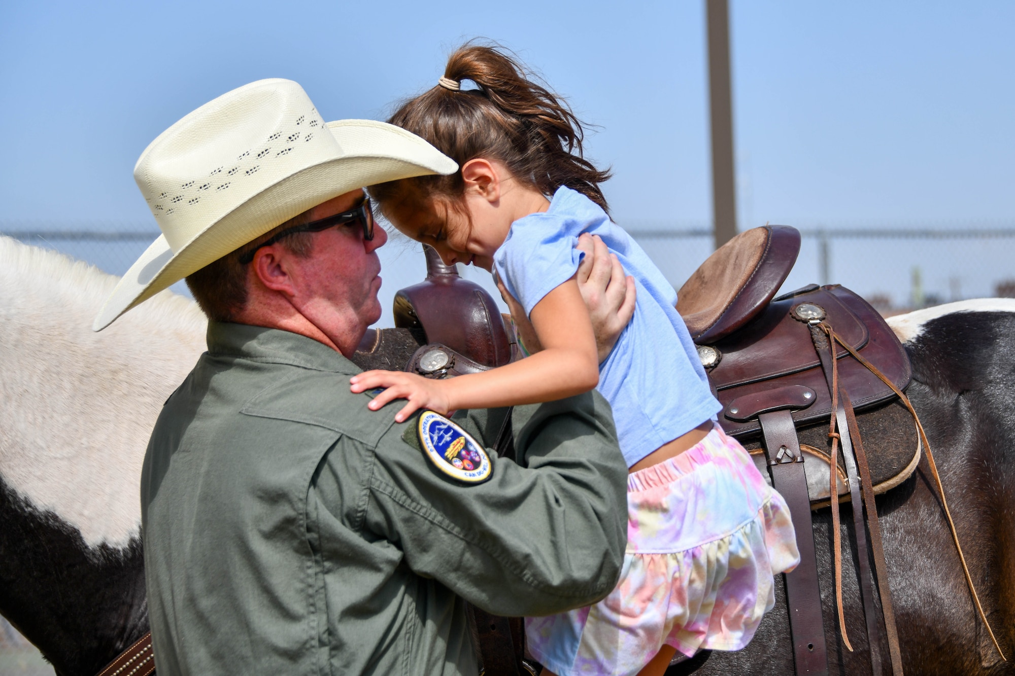 U.S. Air Force Col. John Materson, 97th Operations Group commander, helps Amelia Moore, daughter of Staff Sgt. Joshua Moore, 97th Operations Group enlisted executive officer, during
the annual cattle drive at Altus Air Force Base, Oklahoma, during the 26th Annual Cattle Drive, Aug. 22, 2024. Altus AFB works with the local community to host the cattle drive annually. (U.S. Air Force photo by Senior Airman Miyah Gray)