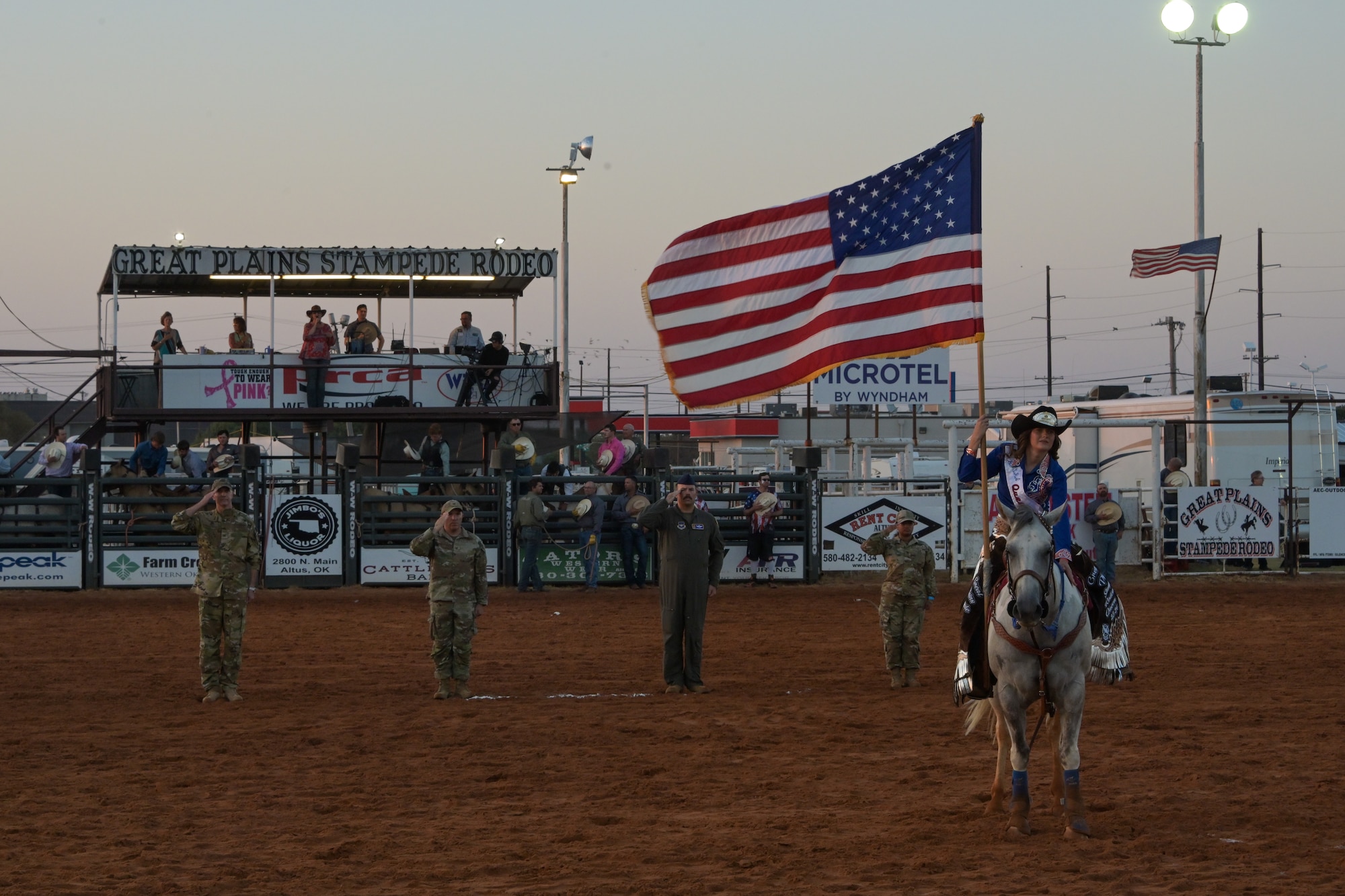 The 97th Air Mobility Wing command team lines up with Senior Airman Sharon Babu, 97th Air Mobility Wing command post operator, to salute the flag during military appreciation night at the 2024 Great Plains Stampede Rodeo in Altus, Oklahoma, Aug. 22, 2024. The Great Plains Stampede Rodeo participants and spectators honored the American flag on military appreciation night. (U.S. Air Force photo by Airman 1st Class Lauren Torres)