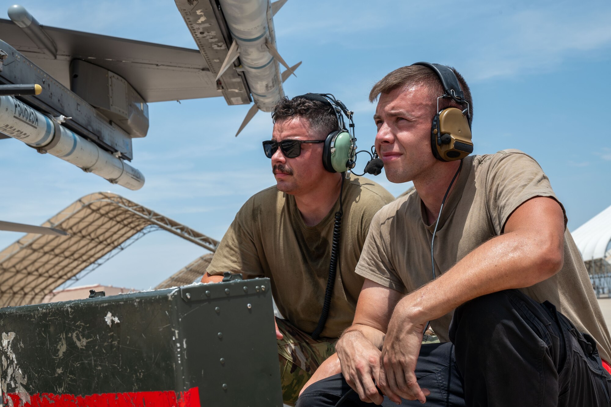 Two men look at an F-16 to inspect it.