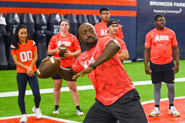 man in orange shirt throwing football