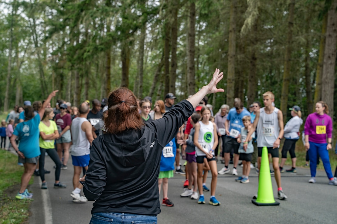 Robyn Gross, a Morale, Welfare and Recreation volunteer, directs race participants to their starting lines during the Deer Run at Naval Magazine Indian Island in Port Hadlock, Washington, Aug. 10, 2024. Approximately 100 runners and walkers participated in this year’s 5k and 1-mile Deer Run, which NMII hosts annually.