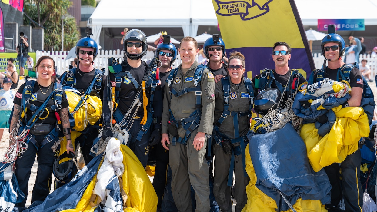 U.S. Air Force Tech. Sgt. Robert Drake, 728th Airlift Squadron loadmaster, and Lt. Col. Heather Huot, 313th Airlift Squadron pilot (middle), pose for a photo after the U.S. Navy Parachute Team demonstration at the Pacific Airshow Gold Coast in Gold Coast, Australia, on Aug. 16th, 2024