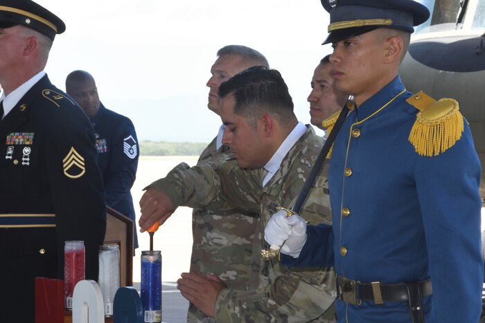 A photo of a service member lighting a candle.