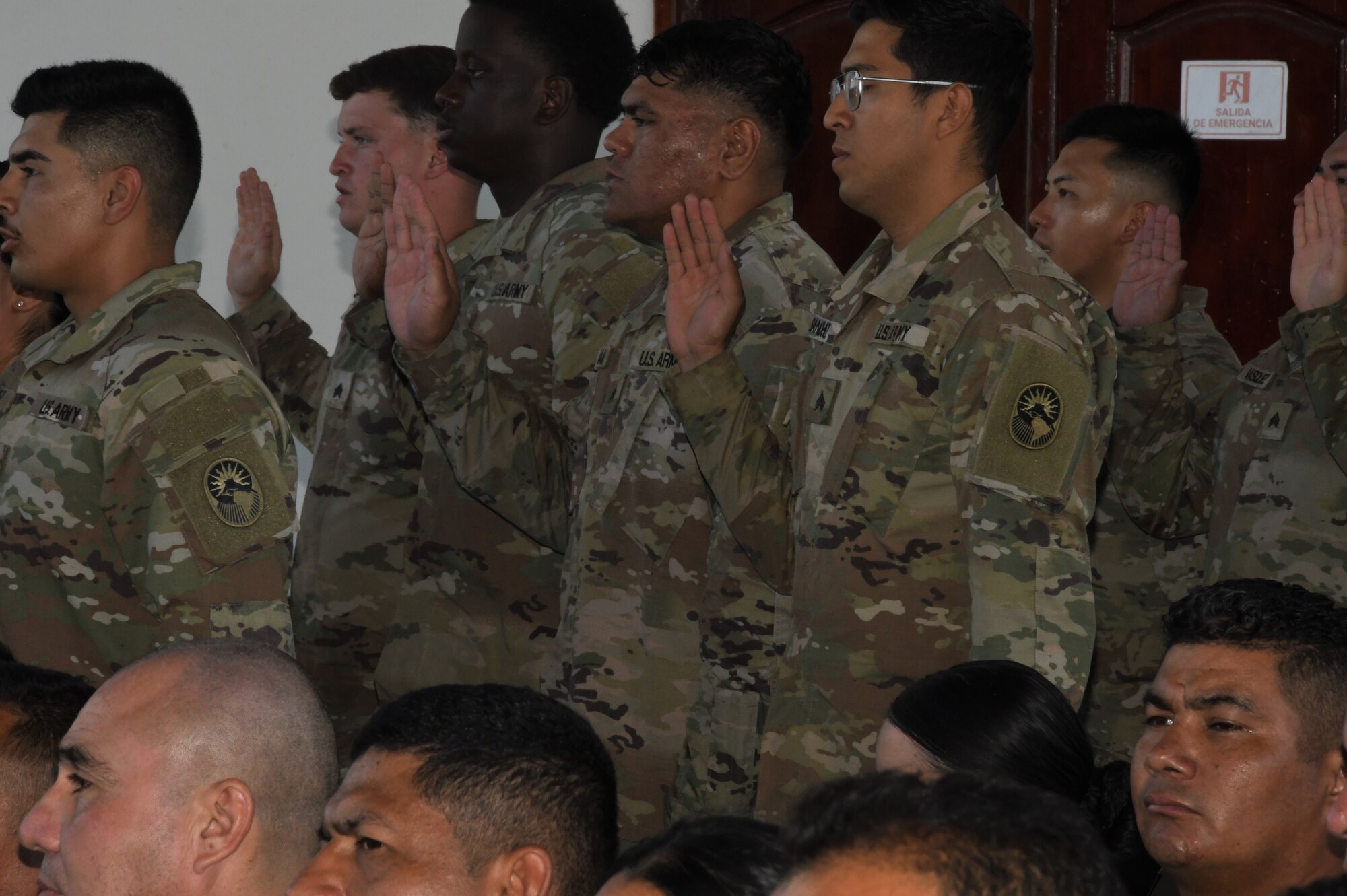 A photo of service members standing with a right hand raised.