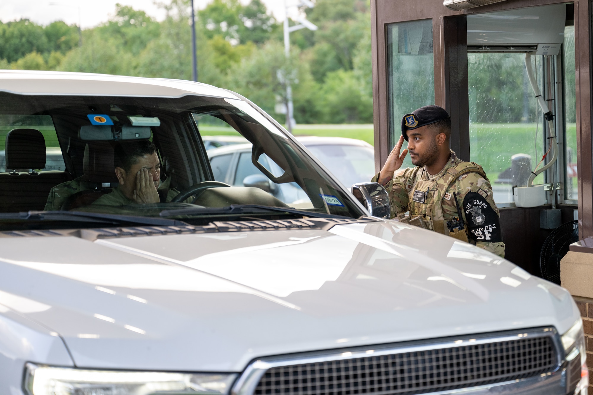 An airman salutes an officer as they drive onto Joint Base Andrews.
