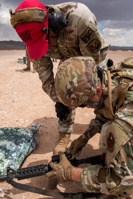 An Airman Cadre assist another Airmen with their weapon as they shoot on the training range