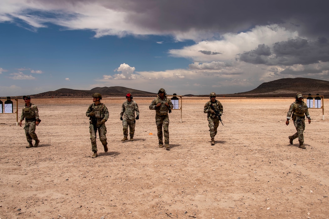 A group of Airmen walk on the rifle range to observe their progress as they train on rifle range