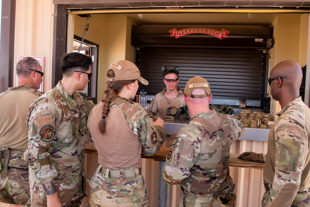 A group of Airmen gather to get ammo from an instructor for the rifle training on the range