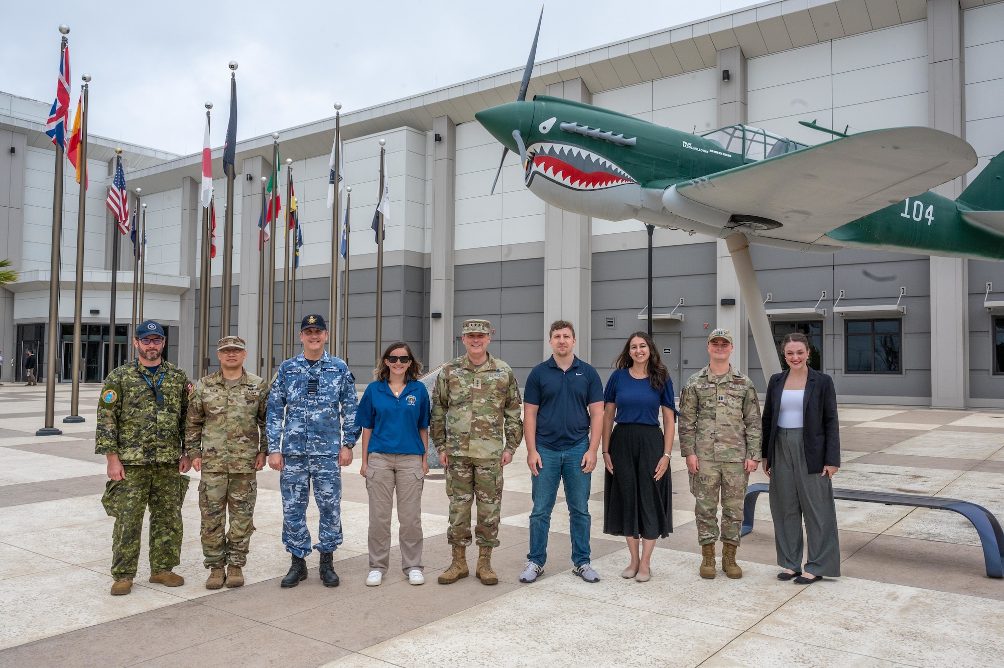 Military and Congressional staff pose in front of a vintage airplane