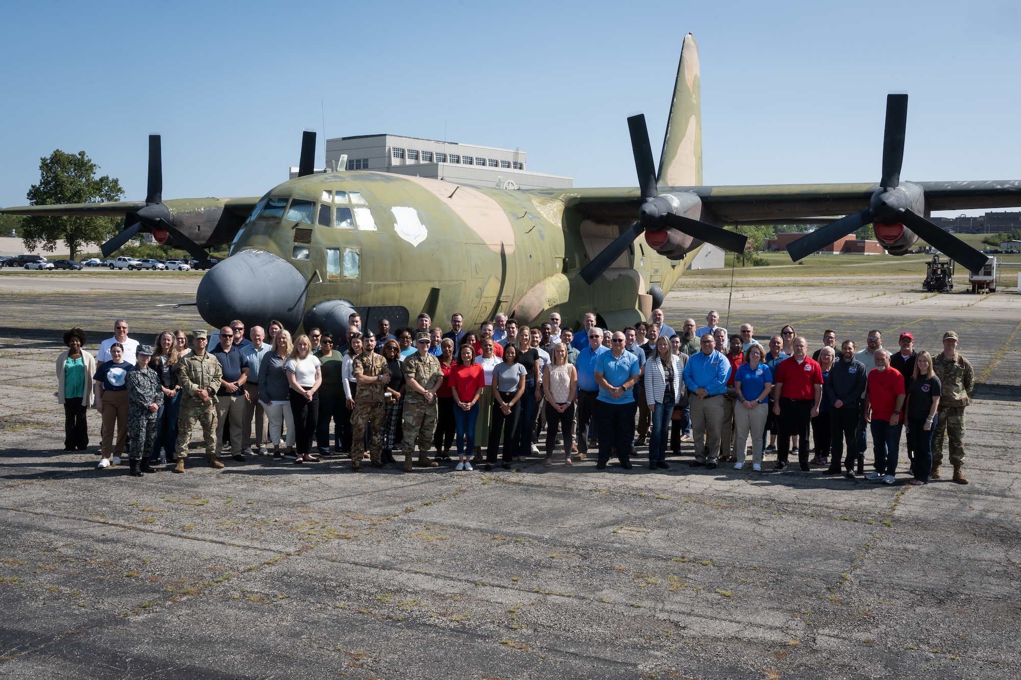 People standing in front of C-130 plane at Air Force base.