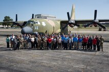 People standing in front of C-130 plane at Air Force base.