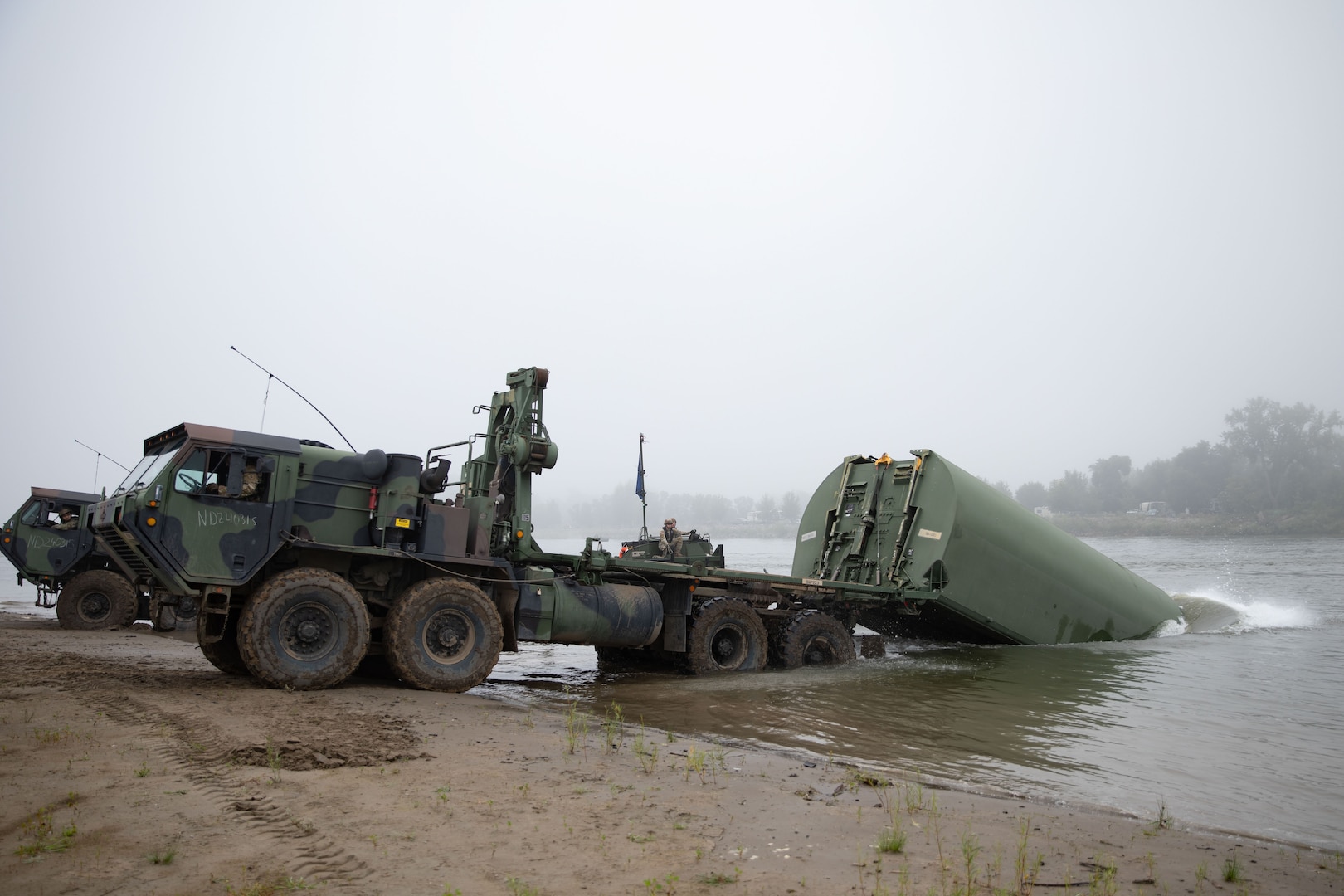 Soldiers with the 957th Multi-role Bridge Company, North Dakota Army National Guard, launch an Improved Ribbon Bridge bay into the Missouri River during a wet gap crossing training exercise near Kimball Bottoms, North Dakota, Aug. 17, 2024. The exercise allowed for cohesive training on complex mission sets.