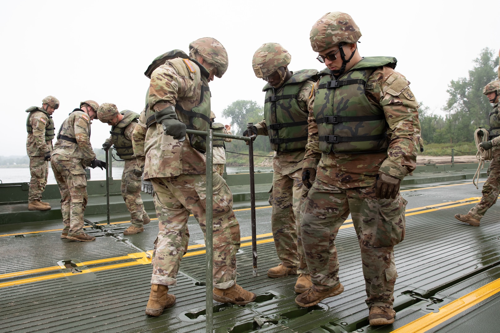 Soldiers with the 957th Multi-role Bridge Company, North Dakota Army National Guard, use T-bars to secure two floating bays of an Improved Ribbon Bridge during a wet gap crossing training exercise on the Missouri River near Kimball Bottoms, North Dakota, Aug. 17, 2024. The exercise tested the unit’s ability to establish vital infrastructure in domestic and combat scenarios.