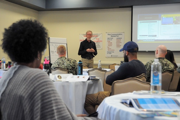 Dr. Paul Gillooly, a risk accessor/risk communicator with the Navy and Marine Corps Force Health Protection Command, educates students during a risk communication workshop Aug. 14, 2024, at the Rivers Edge Conference Center, on Naval Medical Center Portsmouth, Virginia. The risk communication workshop focused on how to plan and execute communications to internal and external stakeholders on any public health issue that impacts their mission. (Navy photo by Desmond Martin)