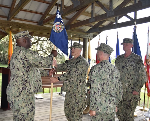 A guidon is passed from Expeditionary Medical Facility 150 Mike incoming Commanding Officer Capt. Jeremy Pyles to EMF-M Senior Enlisted Leader MACS Alvin Jenkins, while outgoing CO Capt. Randy Panke and Naval Hospital Jacksonville Capt. Craig Malloy look on during the Change of Command Ceremony Aug. 23.