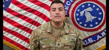 U.S. Army Soldier in uniform poses in front of the American Flag