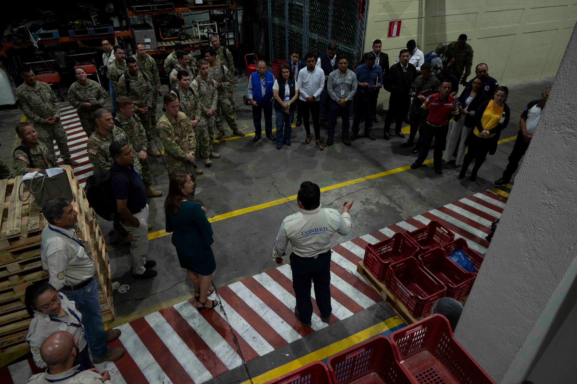 A photo of a person speaking to a large group in a warehouse.