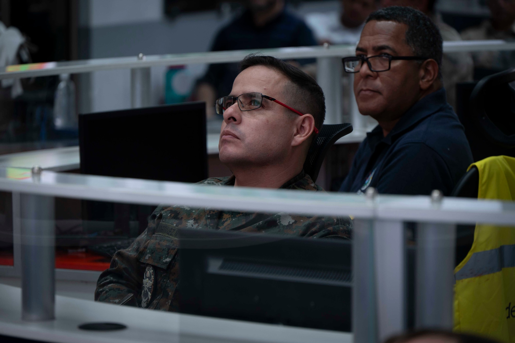 A photo of a man looking at a screen, listening.