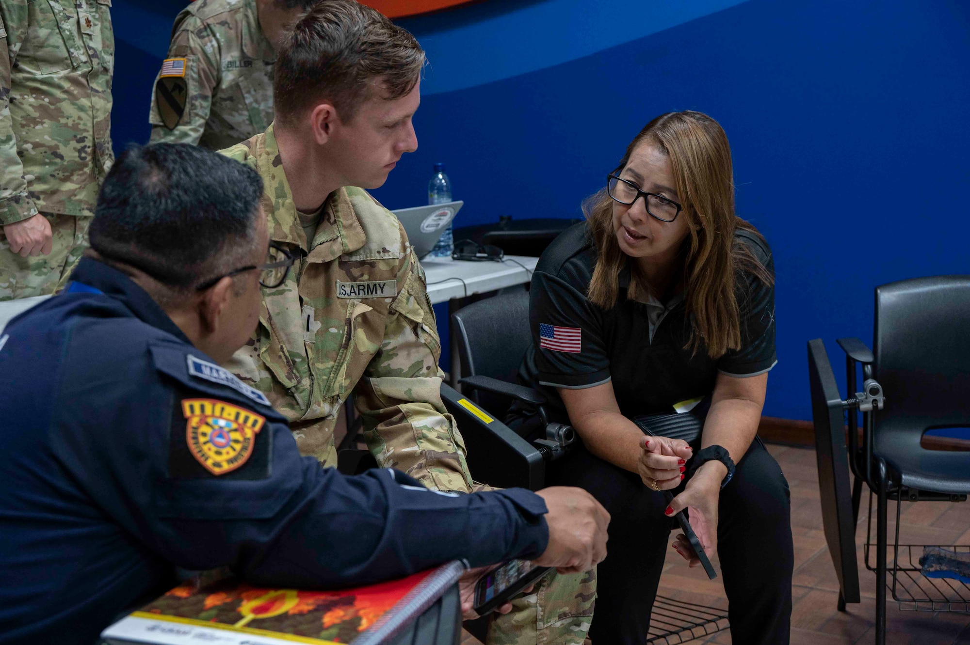 A photo of a woman speaking to two people.