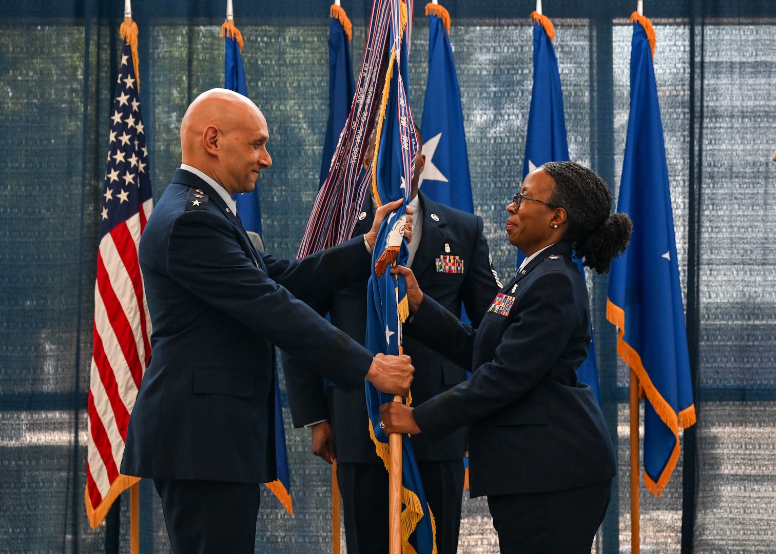 U.S. Air Force Lt. Gen. Brian S. Robinson, Air Education and Training Command commander, passes the guidon to Brig. Gen. Gwendolyn A. Foster, 59th Medical Wing commander, at the 59th MDW change of command ceremony at Joint Base San Antonio, Tx., Aug. 23, 2024.