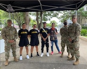 Three U.S. Army Soldiers in uniform pose with Soldiers who are in U.S. Army regulation PT uniforms