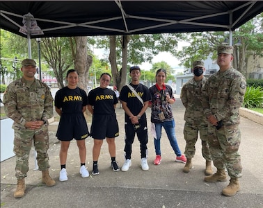 Three U.S. Army Soldiers in uniform pose with Soldiers who are in U.S. Army regulation PT uniforms