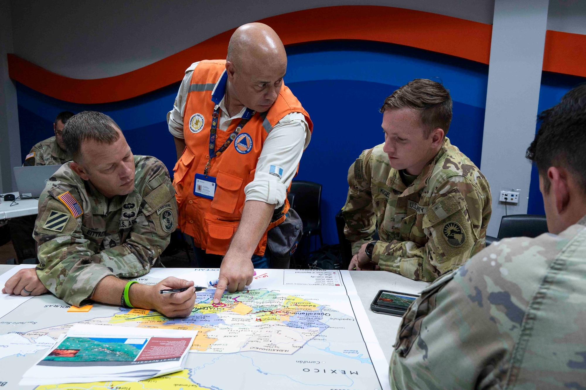 A photo of a person pointing to a map talking to others.