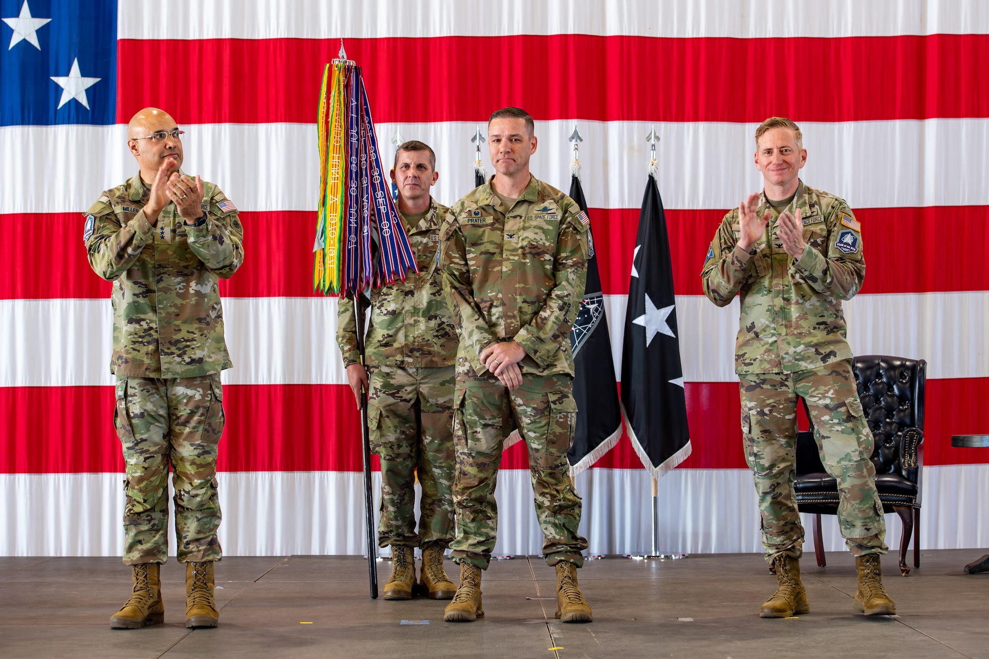 Lt. Gen. David N. Miller, Jr., Space Operations Command commander, left, and Col. Christopher Kennedy, Commander, Space Delta 6, right, clap after Col. Travis Prater, center, officially took command of Space Delta 6 - Space Access and Cyberspace Operations during a change of command ceremony.