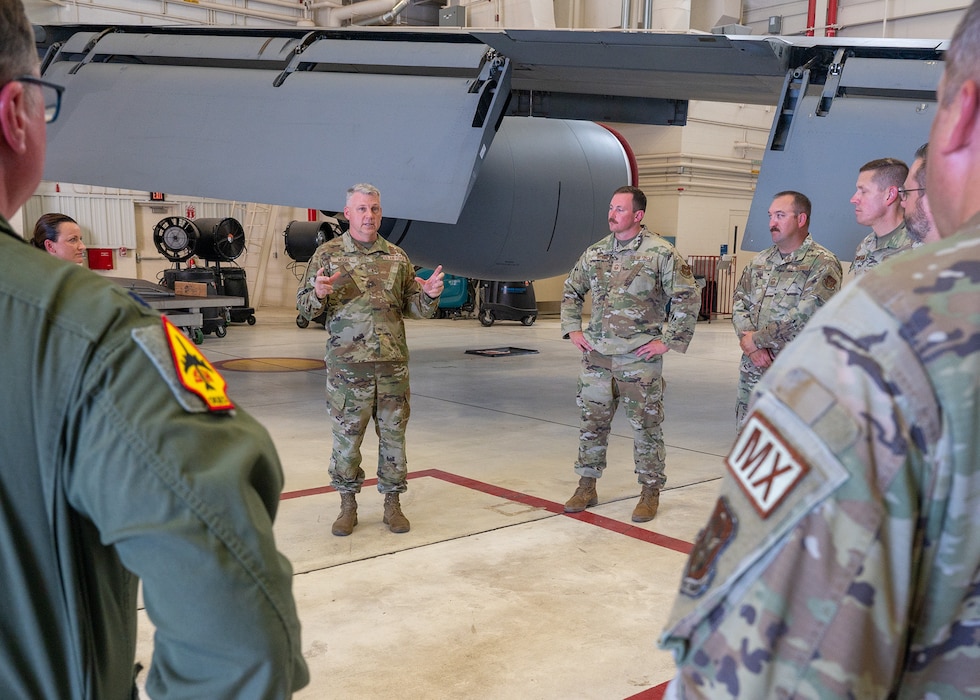 man speaks to group in aircraft hangar