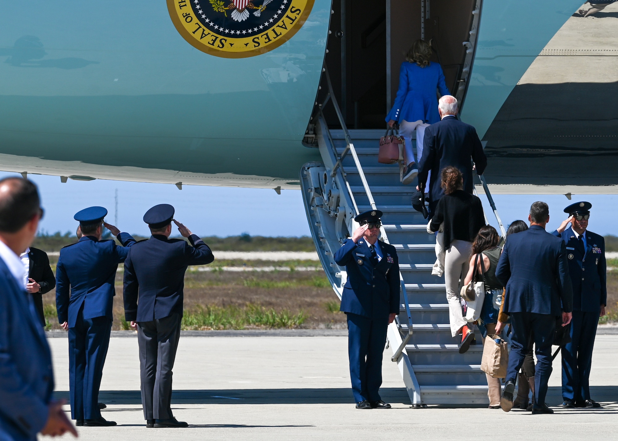 Men in uniform salute President Biden.