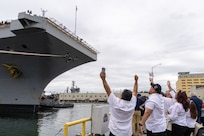 Logistic Specialist Petty Officer Second Class William Aponte waves to family members from the flight deck of USS Ronald Reagan (CVN 76) as the carrier arrives at its new homeport on Naval Base Kitsap-Bremerton, Washington, Aug. 13, 2024. Ronald Reagan served as the U.S. Navy’s only forward-deployed aircraft carrier in Yokosuka, Japan since 2015. (U.S. Navy photo by Wendy Hallmark)