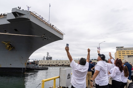 Logistic Specialist Petty Officer Second Class William Aponte waves to family members from the flight deck of USS Ronald Reagan (CVN 76) as the carrier arrives at its new homeport on Naval Base Kitsap-Bremerton, Washington, Aug. 13, 2024. Ronald Reagan served as the U.S. Navy’s only forward-deployed aircraft carrier in Yokosuka, Japan since 2015. (U.S. Navy photo by Wendy Hallmark)