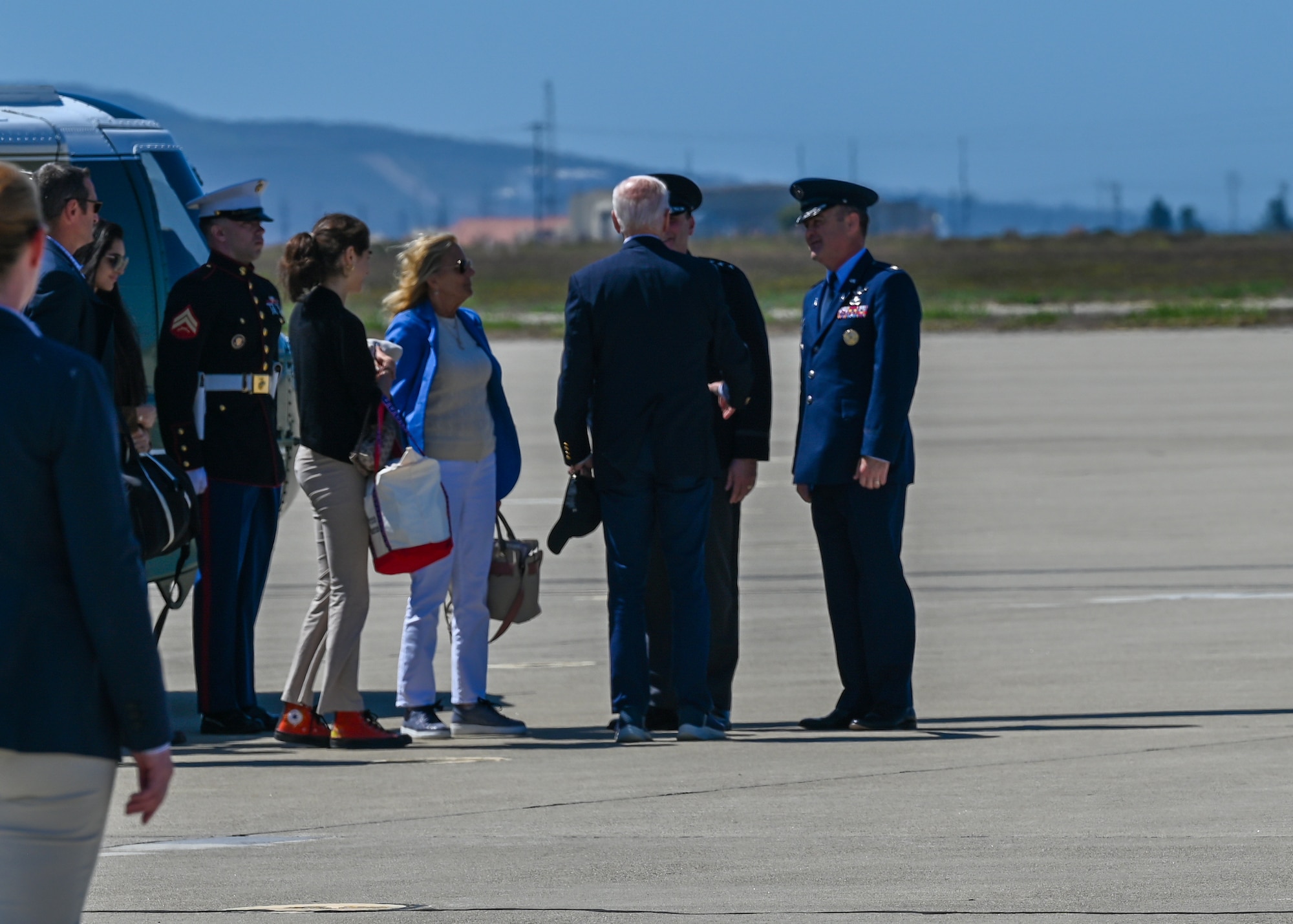 Men in uniform speak with President Biden and Jill Biden.