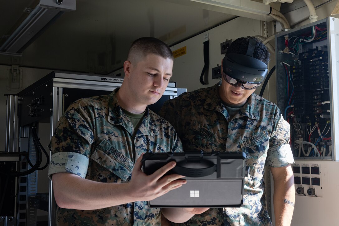 U.S. Marine Corps Cpl. Tyler Havard, left, from Arizona, a ground electronics transmissions systems maintainer with 2nd Maintenance Battalion, 2nd Marine Logistics Group, and Cpl. Vradley Cerna, from Texas, a digital wideband systems maintainer with Marine Wing Communications Squadron (MWCS) 28, test tele-maintenance capabilities at Marine Corps Air Station Cherry Point, North Carolina, Aug. 21, 2024. Marine Depot Maintenance Command is experimenting with augmented reality technology as part of its effort to modernize its maintenance capabilities from industrial-era practices to technologies suitable and capable of meeting the demands of the Information Age. (U.S. Marine Corps photo by Lance Cpl. Orlanys Diaz Figueroa)
