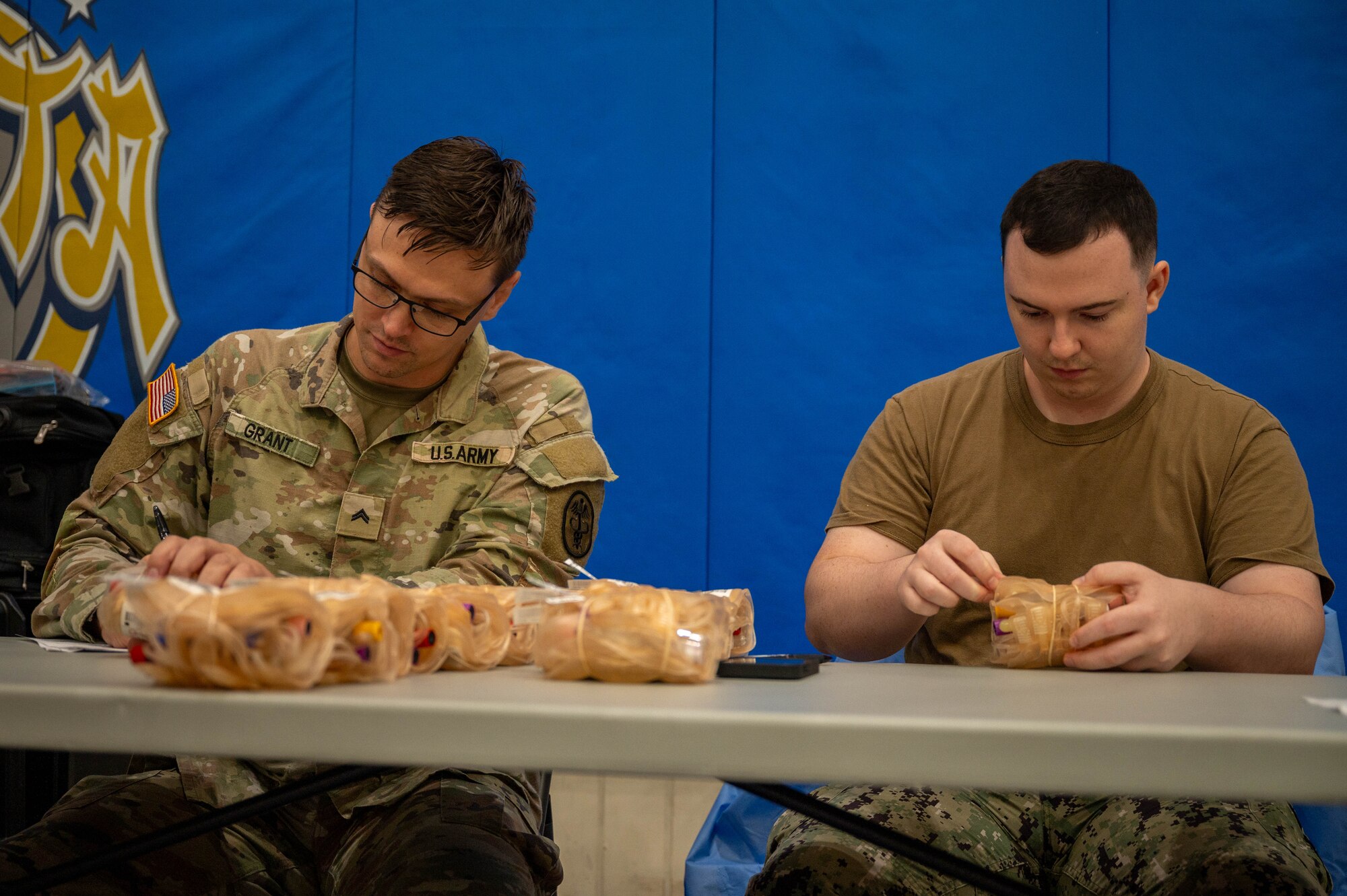 Two service members collect bags of blood.