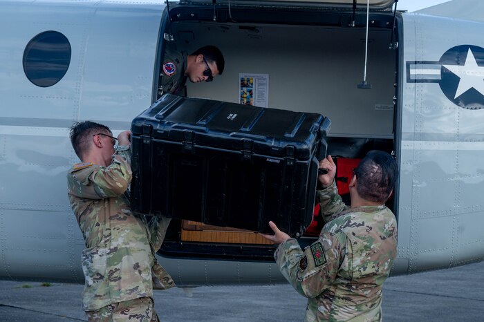 Service members load crate onto a plane.