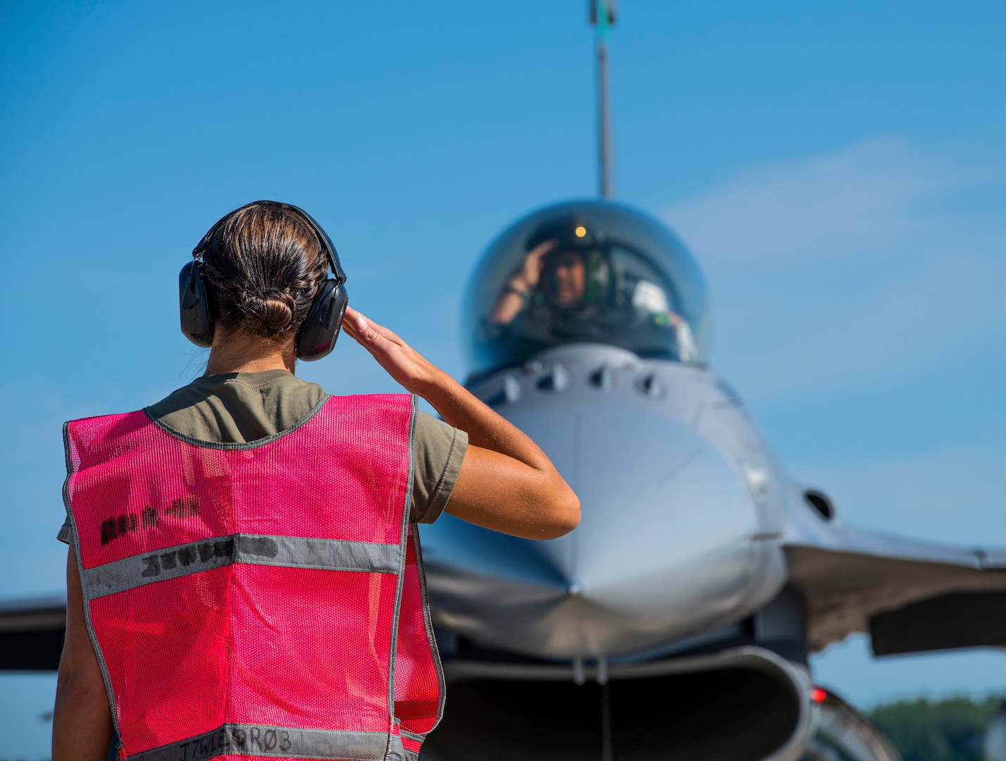 U.S. Air Force Tech Sgt. Erin Luke, a weapons specialist assigned to the Ohio National Guard’s 180th Fighter Wing, salutes an F-16 pilot before takeoff during exercise Northern Lightning at Volk Field, Camp Douglas, Wis., Aug. 7, 2024.