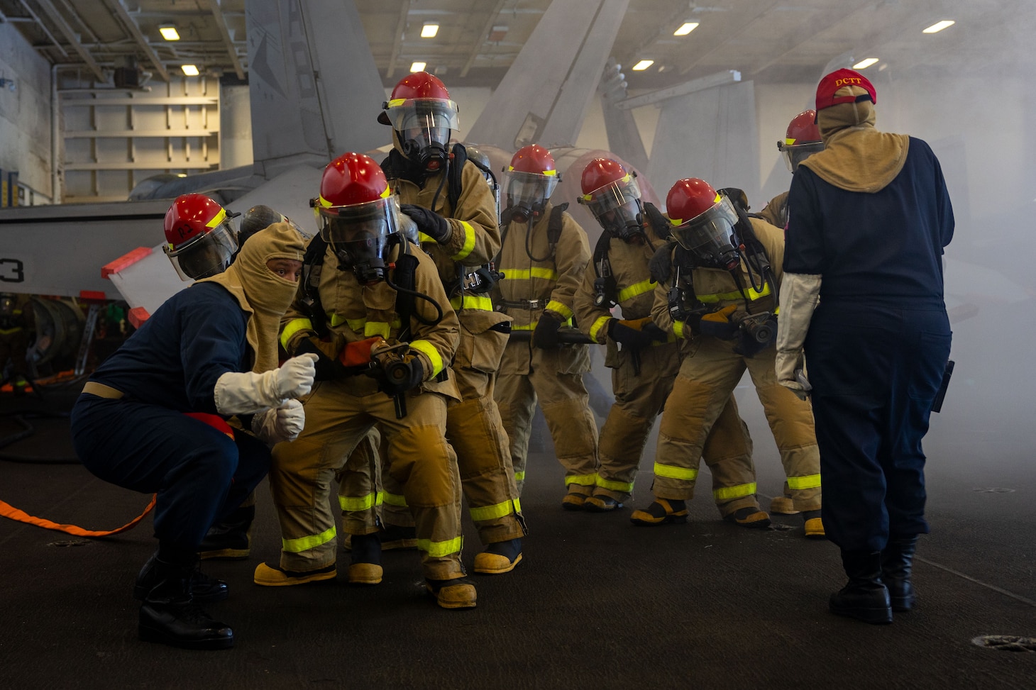 Sailors aboard the Nimitz-class aircraft carrier USS Harry S. Truman (CVN 75), man a hose during a simulated fire in the hangar bay, Aug. 15.