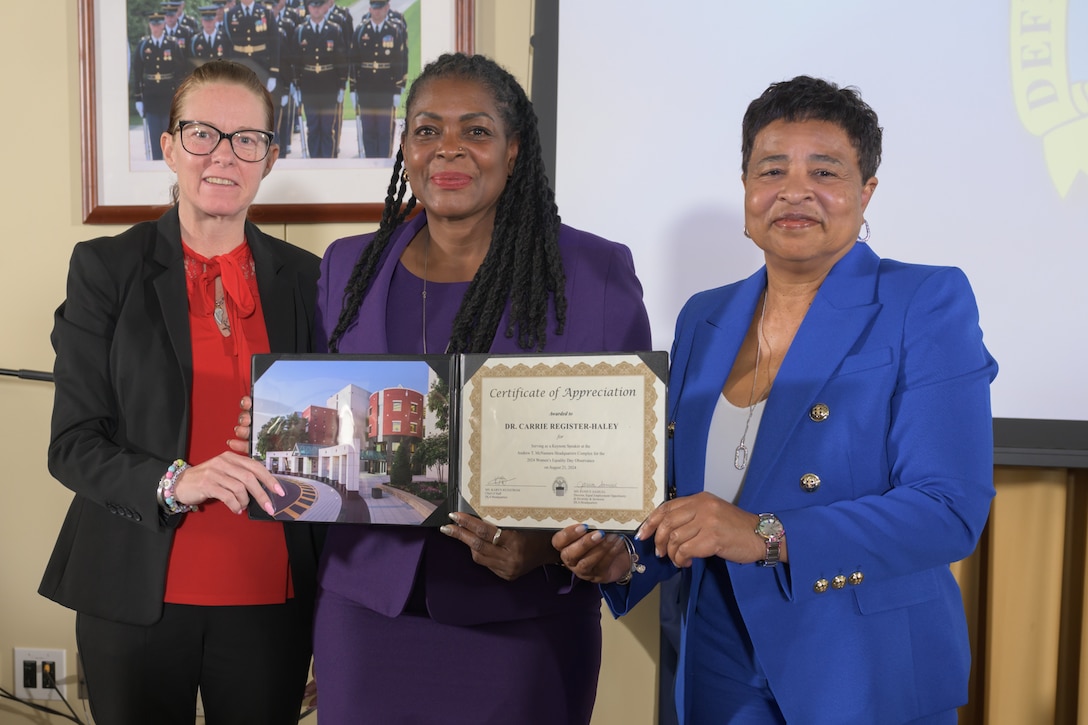 Defense Logistics Agency Chief of Staff Karyn Runstrom, left, and DLA Equal Employment Opportunity Director Janice Samuel, right, present Carrie Register-Haley, center, the founder and CEO of Revelation of Investment Coaching