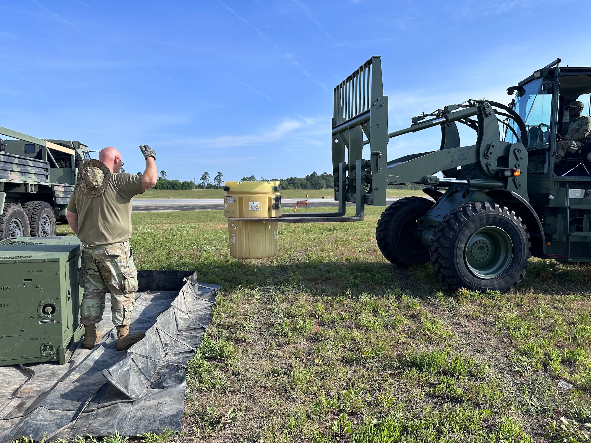 Military man guiding an operator-like vehicle holding a container
