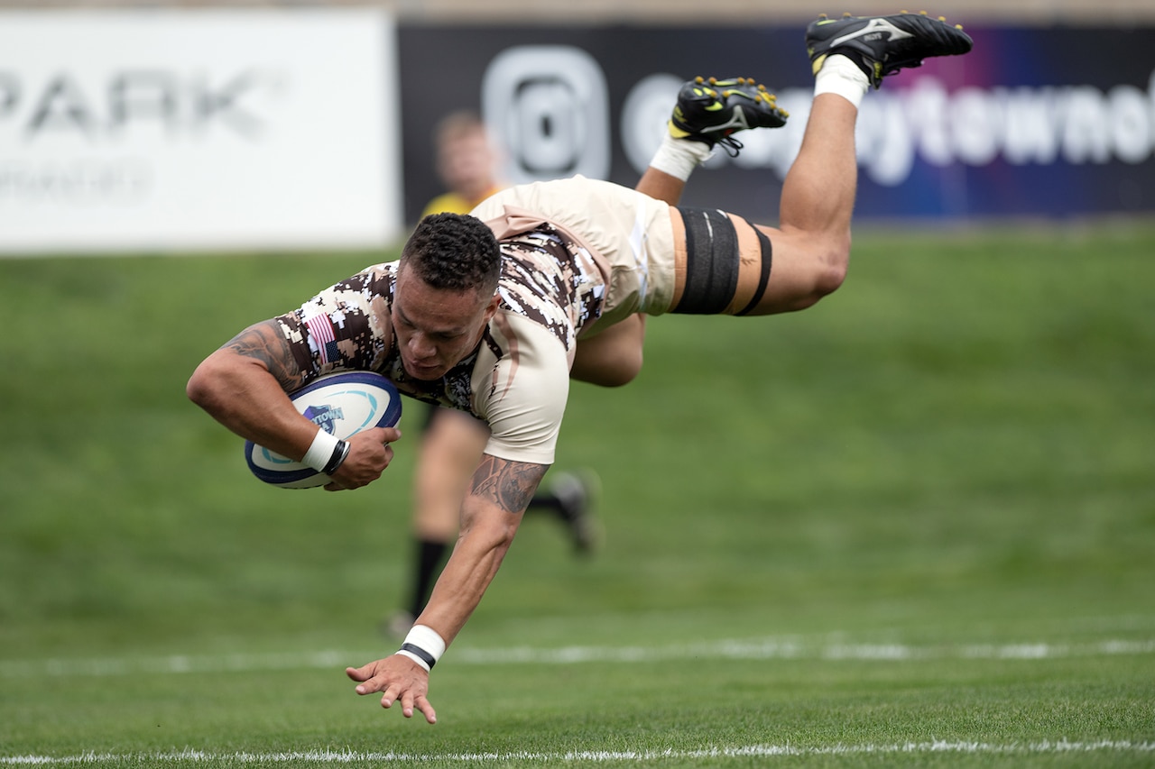 A player with a rugby ball falls to the ground,