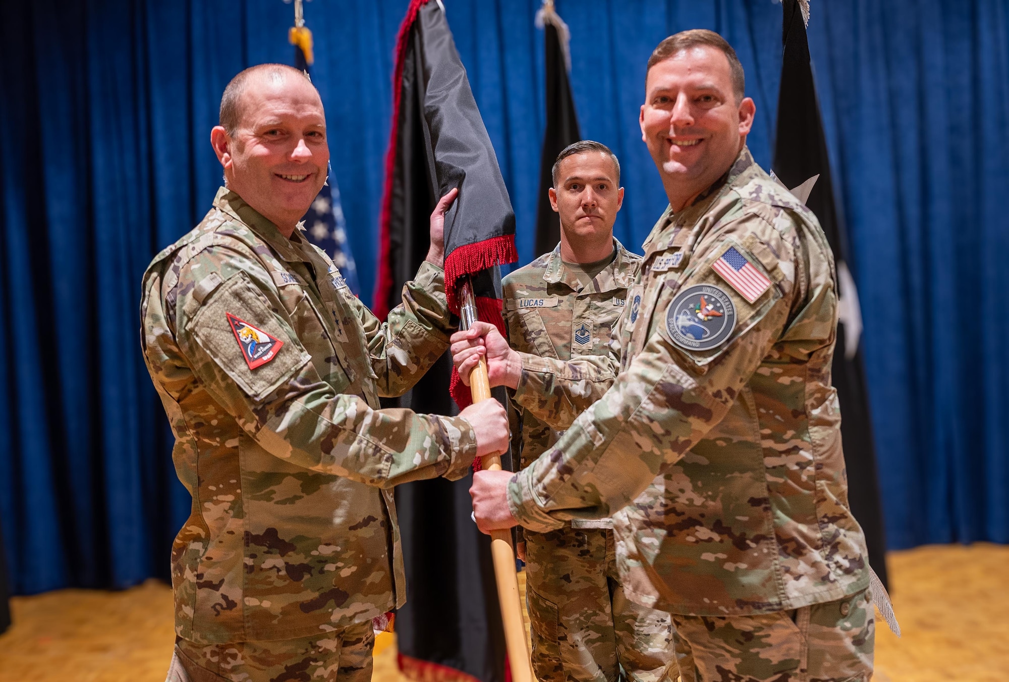 A senior military soldier hands a unit flag off to his commanding officer.