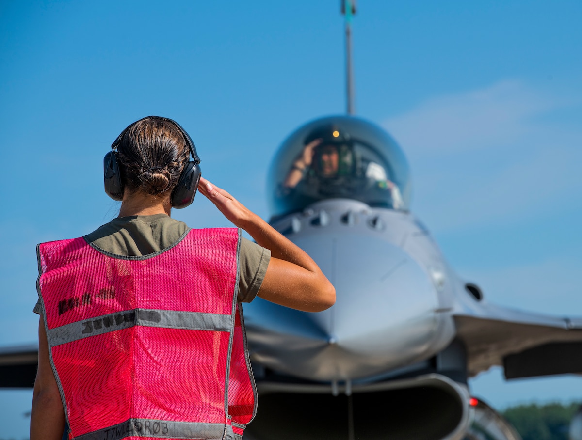 U.S. Air Force Tech Sgt. Erin Luke, a weapons specialist assigned to the Ohio National Guard’s 180th Fighter Wing, salutes an F-16 pilot before takeoff during exercise Northern Lightning at Volk Field, Camp Douglas, Wis., Aug. 7, 2024.