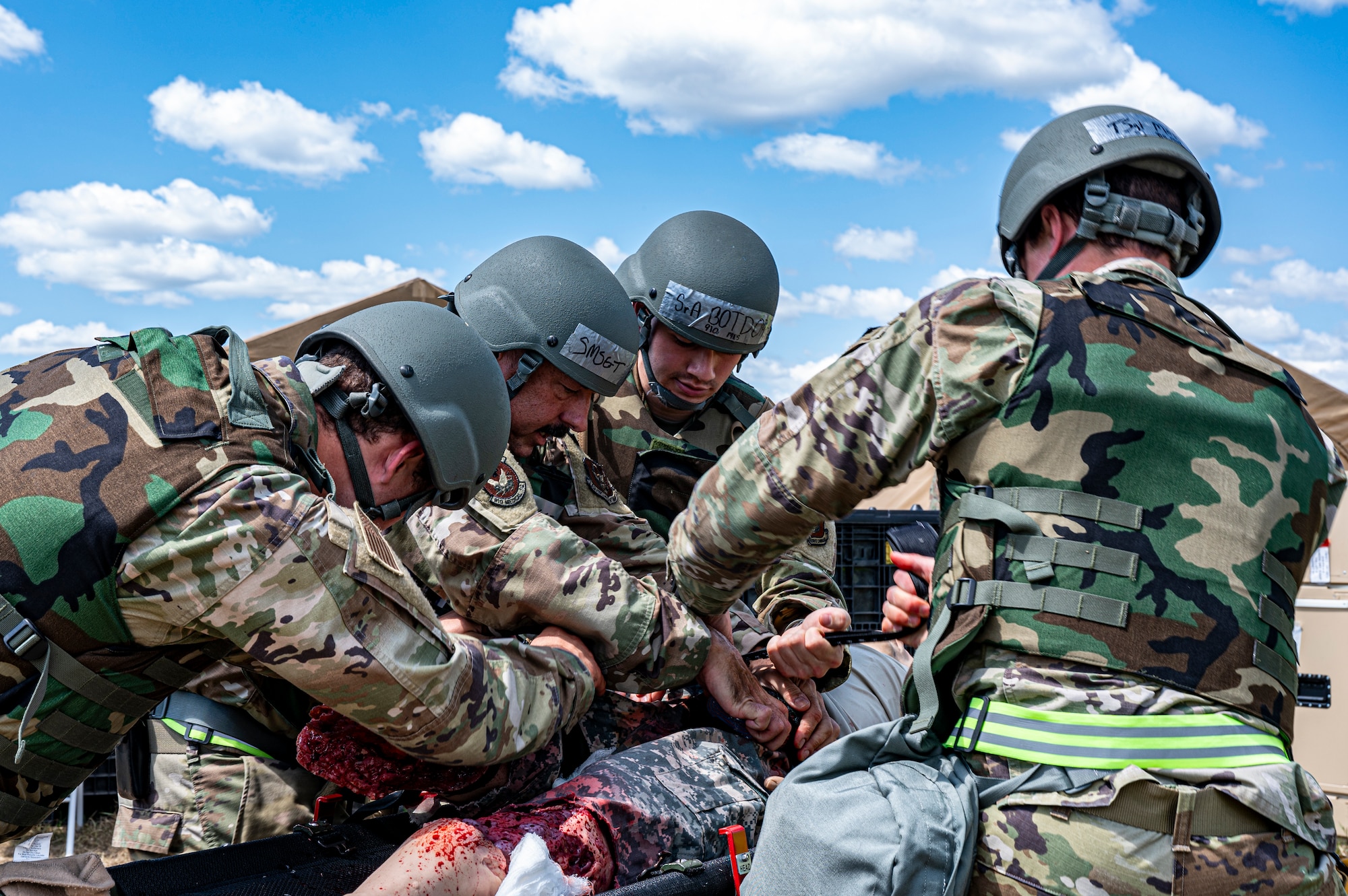 Four Air Force Reserve medics surround a simulated patient casualty outside an Expeditionary Medical Support facility.