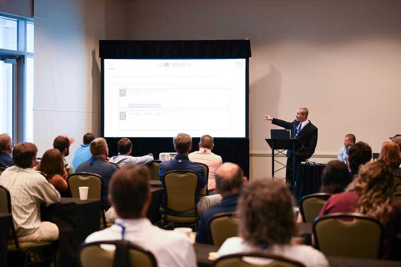 Photo of people sitting down watching a slide presentation.